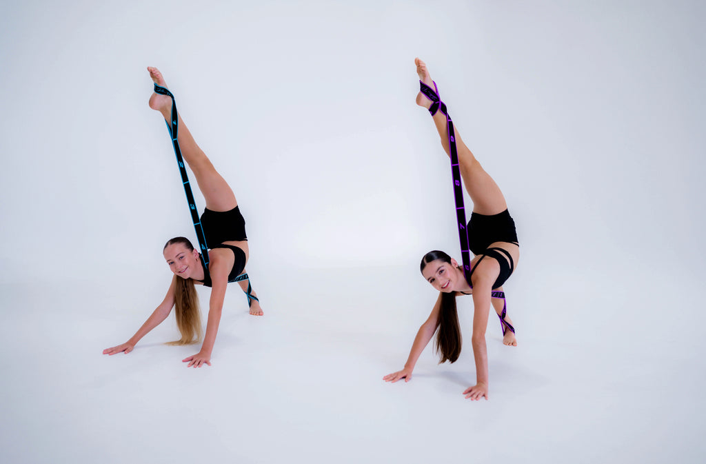 Two dancers performing acrobatic poses with signature stretch bands on a white background