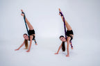 Two dancers performing acrobatic poses with signature stretch bands on a white background